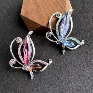 Vintage hollow butterfly brooches with colorful crystals on a dark textured background