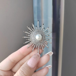 Detail shot of a silver sunflower brooch with a large central pearl and rhinestones