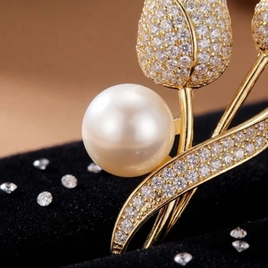 Macro shot of tulip flower brooch with gold finish, sparkling zircons and a white pearl