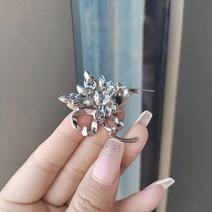 Élégante broche bouquet de fleurs argentée avec cristaux bleu foncé et fermoir épingle