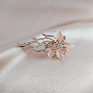 Détail de la broche orchidée or rose avec pétales opale et strass brillants sur soie