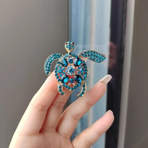 Gros plan détaillé d'une broche tortue dorée ornée de strass bleus étincelants