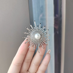Detail view of sunflower brooch with sparkling rhinestones and a large pearl center
