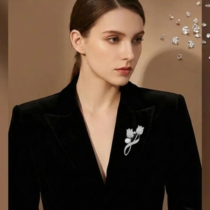 Elegant silver tulip flower brooch with rhinestones and pearl on a black velvet suit jacket