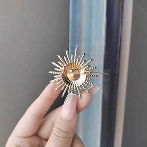 Macro shot of gold sunburst brooch back showing secure pin clasp and metal texture