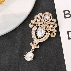 Detaillierte Makroansicht einer goldenen Vintage-Brosche mit Strass und Tropfenkristallen