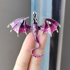 Hand holding a fantasy purple enamel dragon brooch with sparkling rhinestones and wings