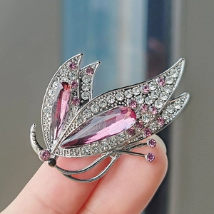 Détail macro de broche papillon avec ailes en cristal rose et monture argentée sur la main