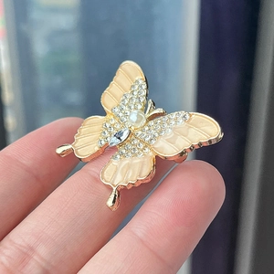 Luxurious butterfly brooch with peach enamel and sparkling crystals on a golden frame