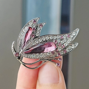 Gros plan sur une broche papillon en cristal avec strass violets sur la main