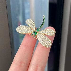 Elegant gold dragonfly brooch with green emerald gems and white crystal accents for coats