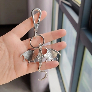Detailed view of a silver dragon keychain charm with spread wings and textured back surface