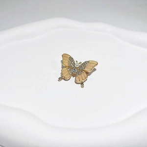 Detailed macro shot of a gold butterfly brooch with rhinestones and a white pearl accent