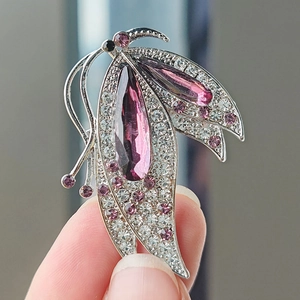 Détail d'une broche papillon avec pierre violette en goutte et cristaux pavés brillants