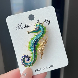 Vintage seahorse brooch with blue-green enamel and sparkling crystal accents on card
