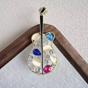 Broche guitare dorée avec opale évidée et pierres précieuses sur support en bois