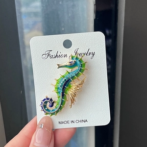 Vintage gold seahorse brooch with blue-green enamel and sparkling rhinestones on card