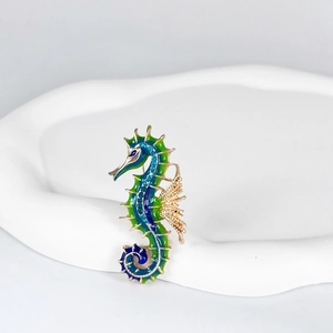 Macro detail of seahorse brooch with blue-green enamel inlay and dark blue crystals
