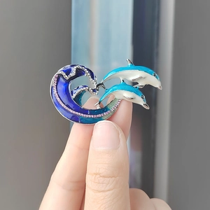 Elegante spilla a forma di delfino con smalto blu e cristalli lucenti su un'onda d'argento