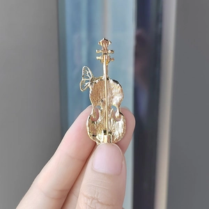 Back view of a gold violin brooch with butterfly detail and secure pin clasp mechanism