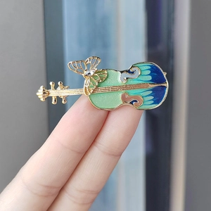 Detailed close-up of violin brooch with blue gradient enamel and butterfly accent