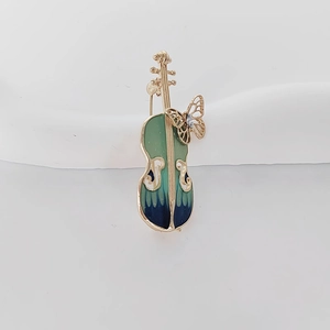 Macro detail of violin brooch featuring blue gradient enamel and a golden butterfly