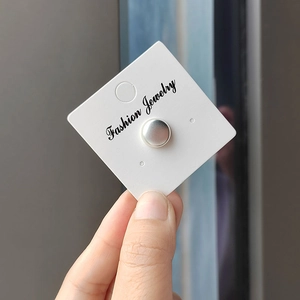 Detailed view of a silver magnetic brooch for hijabs on a white display card holder