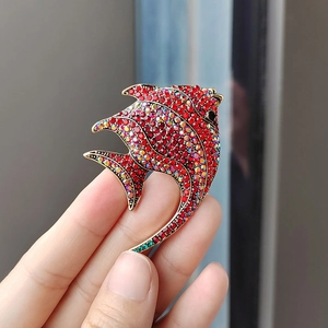 Close-up of tropical fish brooch with red and rainbow crystals held by hand