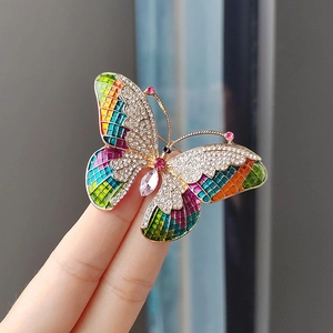 Macro detail of butterfly brooch with colorful enamel wings and crystal teardrop