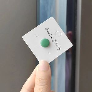 Detailed close-up of a round matte green magnetic hijab pin on a white display card