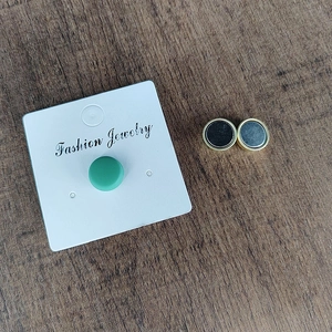 Minimalist round magnetic shawl clips and green studs displayed on a rustic wood background