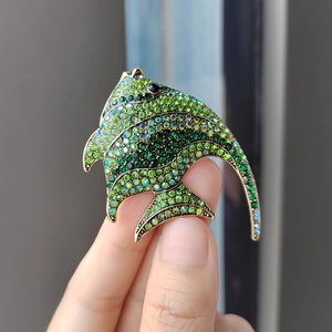 Exquisite tropical fish brooch with green crystals and gold base in hand-held macro view