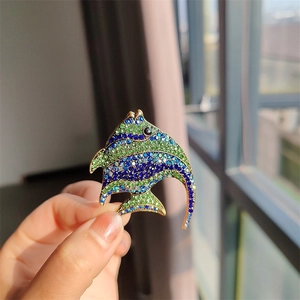 Close-up of tropical fish brooch with sparkling green and blue rhinestones on gold metal