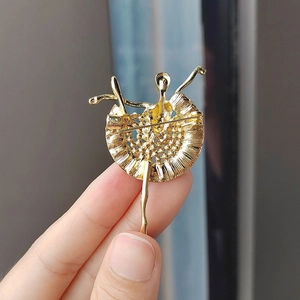 Detalle del reverso del broche de bailarina dorado con cierre de alfiler y falda de malla