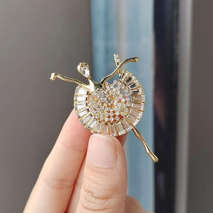 Detalle de elegante broche de bailarina dorado con pavé de cristales y circonitas