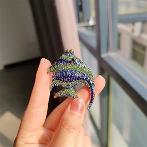 Detail of tropical fish brooch with vibrant blue and green rhinestones in gold setting