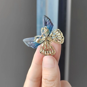 Detalle de broche de mariposa degradado azul violeta con metal dorado calado y purpurina
