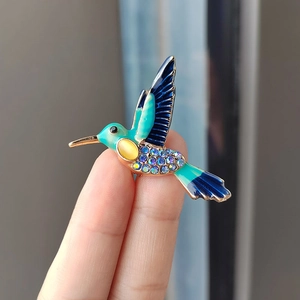 Detaillierte Handaufnahme einer Kolibri-Brosche mit buntem Emaille und Strasssteinen