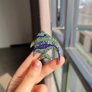 Close-up of a tropical fish brooch with blue and green rhinestones in hand