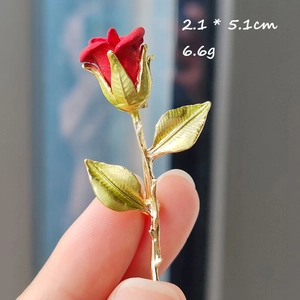 Vista detallada del broche de rosa con capullo rojo y hojas doradas de 2,1x5,1cm
