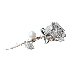 Elegant silver rose brooch with sparkling rhinestones and a white pearl accent on white background
