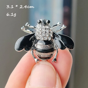Vue rapprochée d'une main tenant la broche abeille de 3,1 x 2,4 cm avec zircons scintillants