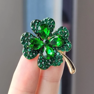 Close-up of four-leaf clover brooch with green rhinestones and golden metal detail