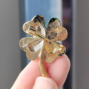 Detailed back view of golden clover brooch showing safety pin and green enamel edges