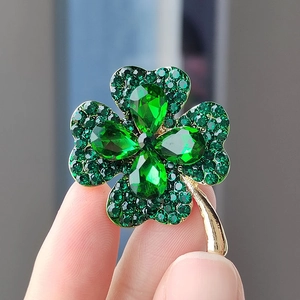 Elegant four-leaf clover brooch featuring green cat-eye stones and a golden finish