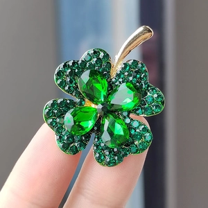 Elegant four-leaf clover brooch with green gemstones and sparkling crystals in gold setting