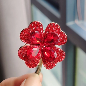 Minimalist red opal four-leaf clover brooch featuring ruby-red crystals in gold setting