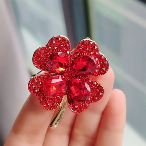 Detailed close-up of a red cat eye clover brooch featuring sparkling red rhinestones