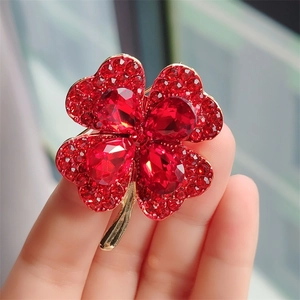 Detailed view of red clover brooch with sparkling crystals and gold-plated finish