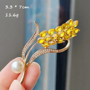 Détail d'une broche épi avec cristaux jaunes et perle blanche, taille 3,3x7cm